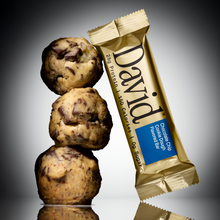 Three chocolate chip cookies dough balls stacked with a David protein bar on a gray background