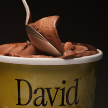 Spoon dipping into a container of chocolate ice cream branded 'David' on a black background