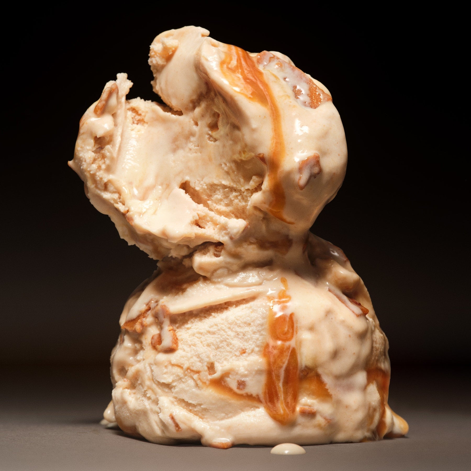 Ice cream sculpture with peanut butter drizzle on a dark background